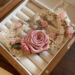 Gros plan détaillé du tour de cou en dentelle vintage avec rose en satin et perles fines.