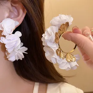 Detailed view of white chiffon flower C-shape earrings with gold leaves