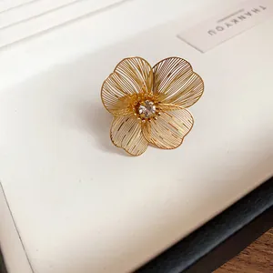 Detailed close-up of a gold hollow floral bracelet with central rhinestone inlay