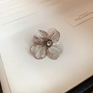 Detail of silver metal cuff with hollowed floral petals and a sparkling rhinestone center cluster