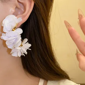 Close-up detail of elegant white chiffon fabric flower C-shaped stud earrings for women