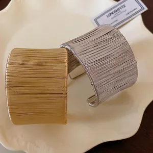 Elegantes brazaletes abiertos envueltos en oro y plata presentados en un plato blanco