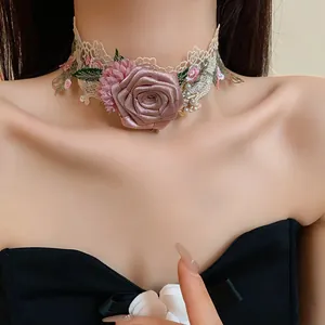 Gros plan du ras-du-cou en dentelle Mori avec une grande rose en tissu 3D rose et perles
