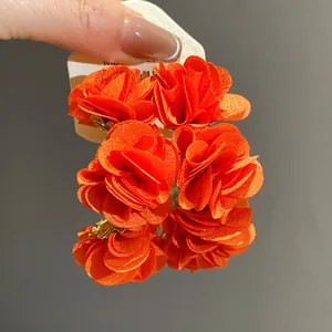 Detailed close-up of vibrant orange chiffon flower earrings showing soft fabric layers