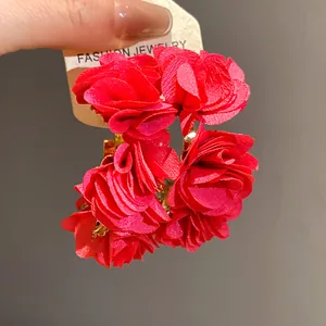 Close-up of red chiffon rose fabric C-shaped earrings with gold hoops