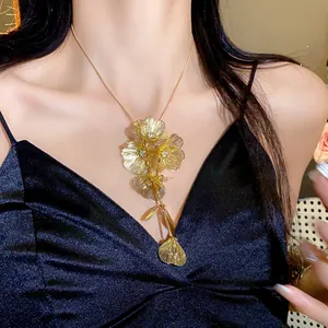 Detailed view of a gold floral pendant necklace with sparkling rhinestones on a female model