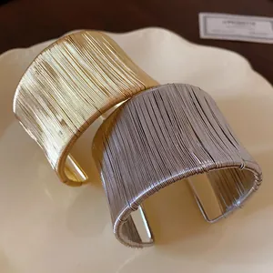 Primer plano de la textura de hilo enrollado en los brazaletes abiertos de oro y plata