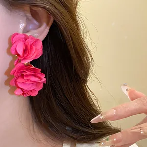 Detailed close-up showing vibrant rose pink chiffon flower earrings on a model's ear