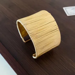 Vista detallada del brazalete dorado de alambre enrollado con acabado texturizado