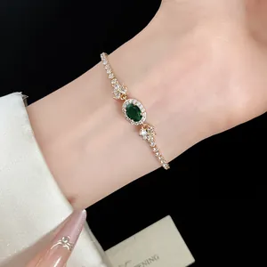 Detailaufnahme eines eleganten goldfarbenen Armbands mit grünem Zirkonanhänger