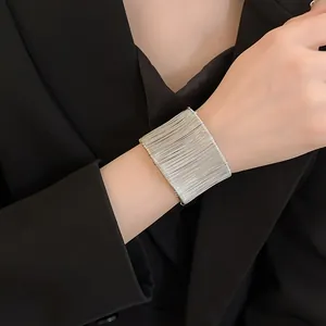 Detalle que muestra un brazalete ancho de hilo de plata enrollado usado en la muñeca