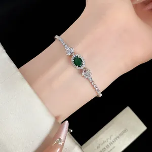 Elegantes grünes ovales Zirkon-Armband am Handgelenk einer Frau mit glänzenden Steinen
