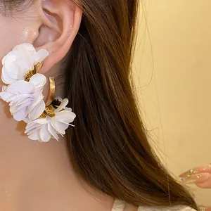 Exquisite close-up detail of white chiffon flower C-shaped earrings worn by a model