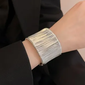 Vista detallada de un elegante brazalete abierto plateado de varios hilos enrollados