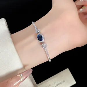 Detailaufnahme eines eleganten Silberarmbands mit blauem Zirkonstein am Handgelenk.