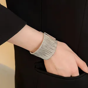 Primer plano de un brazalete plateado envuelto en alambre en una muñeca con blazer
