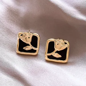 Detailed view of French vintage gold rose square stud earrings on elegant silk fabric