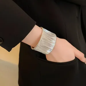 Detalle de un brazalete abierto de hilo de plata minimalista en la muñeca de una modelo