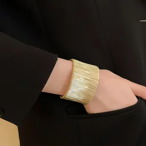 Primer plano de un elegante brazalete ancho dorado envuelto en una muñeca femenina