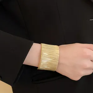 Primer plano de un brazalete ancho de hilo dorado enrollado en la muñeca