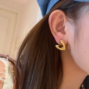 Close-up of a French vintage gold heart-shaped stud earring worn on a model's ear lobe