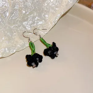 Handmade knitted black flower earrings with green stems and silver hooks for women