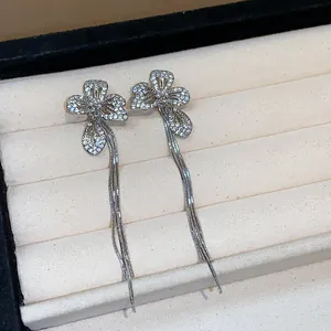 Dettaglio di orecchini a fiore con nappe argentati con zirconi e perle raffinate