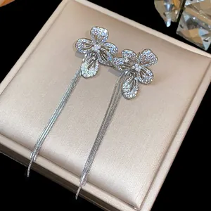 Dettaglio macro di orecchini a fiore in zircone con lunghe nappe in argento frangia
