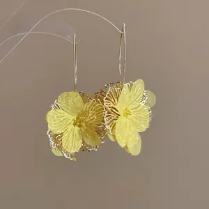 Delicate yellow fabric hollow flower earrings with thin gold-tone ear hooks for a gentle look