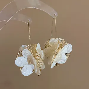 Close-up of elegant hollow flower earrings with gold hooks and white fabric petals