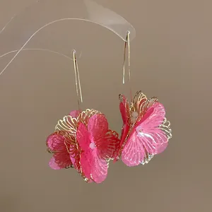 Close-up of elegant dopamine hollow flower hook earrings featuring pink fabric and gold metal