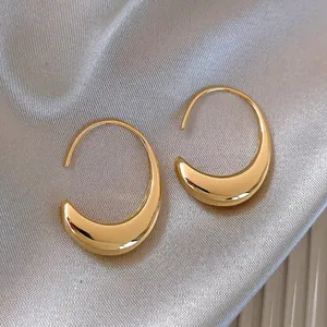 Detailed macro view of golden minimalist geometric crescent earrings on champagne silk