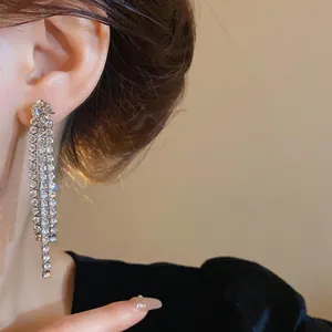 Primo piano di lunghi orecchini a nappa con strass scintillanti indossati con eleganza