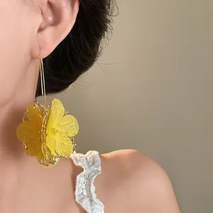 Detailed view of elegant yellow translucent flower ear hooks worn by a model for a soft look