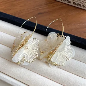 Close-up of elegant vintage hollow flower drop earrings with white mesh petals and gold hooks.