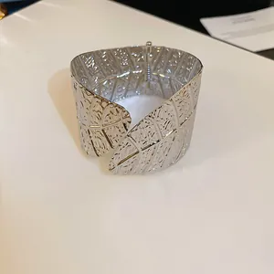 Close-up of a silver-toned wide cuff bracelet featuring detailed leaf vein textures.