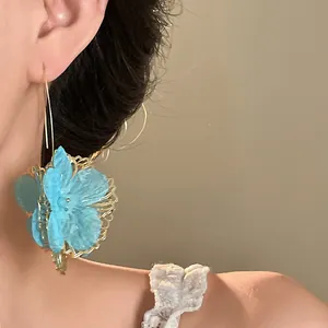 Close-up detail shot of a vintage hollowed blue flower earring on a model ear, elegant style