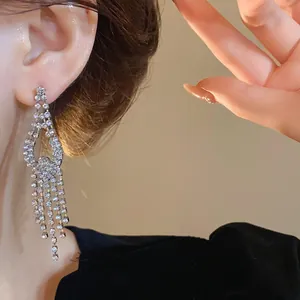 Dettaglio di orecchino con nappe in strass argentati con un elegante luccichio sul viso.