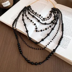 Elegant multi-layered black beaded sweater chain necklace displayed on a vintage book page