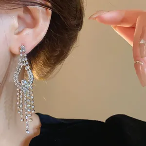 Primo piano dettagliato di eleganti orecchini a nappa con strass indossati su un orecchio