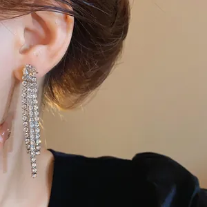 Vista ravvicinata di eleganti orecchini pendenti con nappe di strass argento sul modello