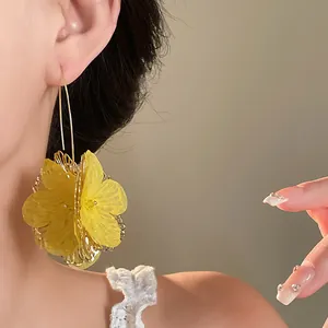 Close-up of elegant yellow hollow mesh flower ear hook earrings on a model ear