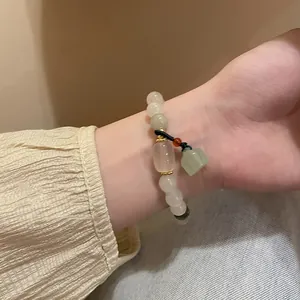 Detailaufnahme eines handgefertigten Perlenarmbands mit einem jadegrünen Anhänger am Handgelenk