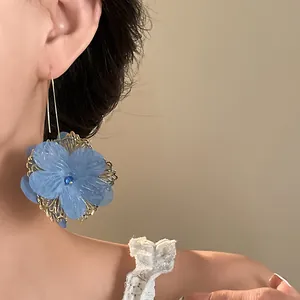Detailed view of elegant vintage blue hollow flower hook earrings on an Asian model