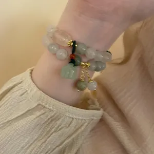 Detailansicht eines eleganten, zweireihigen Perlenarmbands in sanften Grün- und Rosatönen.