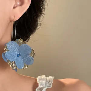 Detailed close-up showing elegant blue fabric flower drop earrings with vintage gold lace design