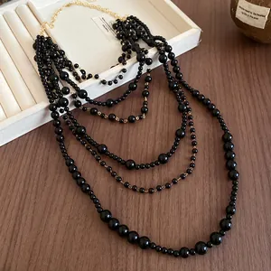 Detail view of a multi-layer retro necklace with black acrylic beads and gold chain