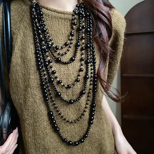Close-up of vintage multi-layered black acrylic bead necklace worn over a brown sweater