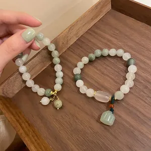 Nahaufnahme von handgefertigten Perlenarmbändern mit grünen Jade-Anhängern auf Holz.