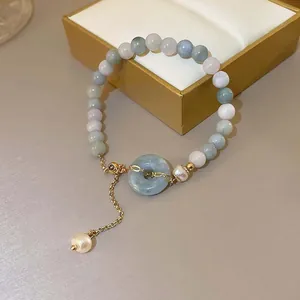 Nahaufnahme eines Jade-Perlenarmbands mit Donut-Anhänger und hängendem Perlendetail.